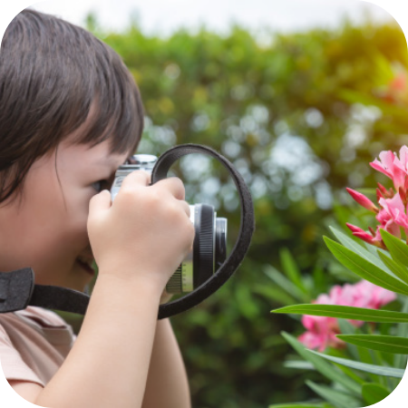 child taking a photo of a flower